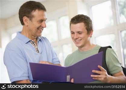 Teacher in corridor talking to student with notebooks