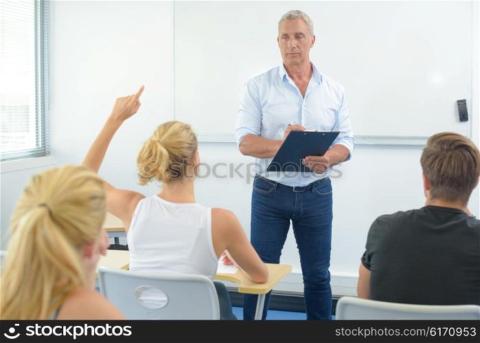 Teacher in front of class, student with arm raised