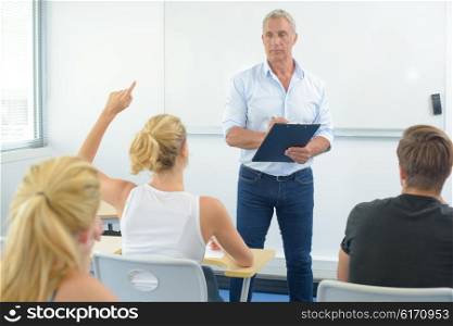 Teacher in front of class, student with arm raised