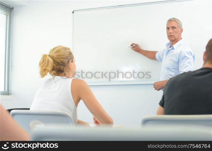 teacher in front of white board in classroom