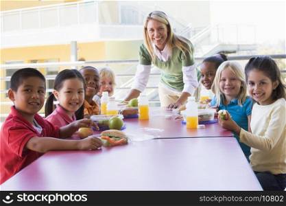 Teacher leaning on table outdoors while students eat lunch (high key)