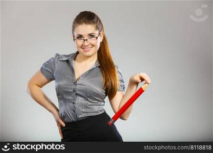 Teacher looking elegant woman wearing dark tight skirt, shirt and eyeglasses holding big oversized pencil. Teacher looking elegant woman holding big pencil