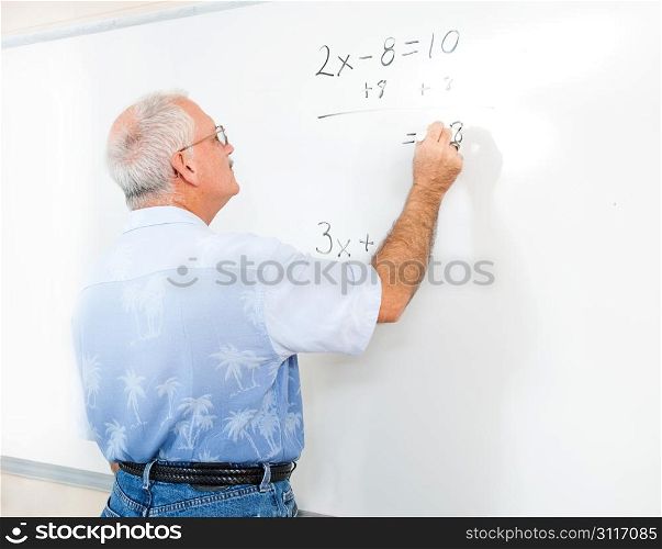 Teacher or adult student writing an algebra problem on the blackboard.