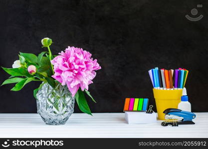 Teacher or student desk table. Education background. Education mockup concept. Scattered colour pencils, blank paper page, stacked books, green plant tree, pencil holder on blackboard background.. Teacher or student desk table. Education background.