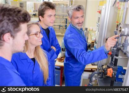 Teacher pointing to machine, everyone smiling