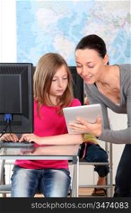 Teacher showing electronic tablet to school girl