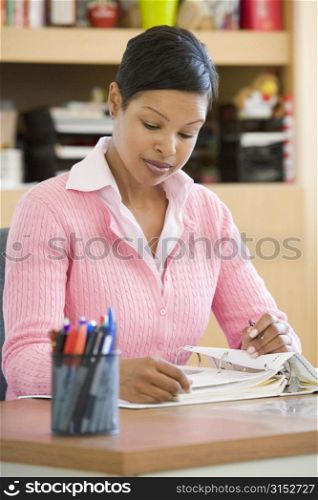 Teacher sitting in class at desk looking at notes (selective focus)