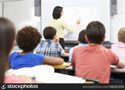 Teacher Standing In Class Using Interactive Whiteboard
