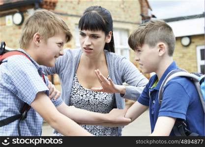 Teacher Stopping Two Boys Fighting In Playground