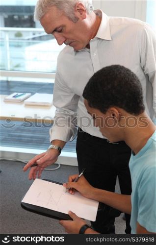 Teacher supervising his student&rsquo;s work