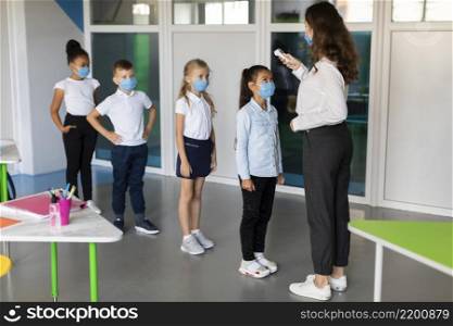 teacher taking temperature her students