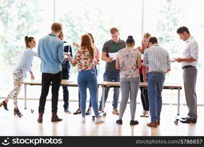 Teacher With College Students Standing By Desks In Classroom