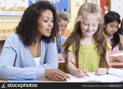 Teacher With Female Elementary School Pupil In Class