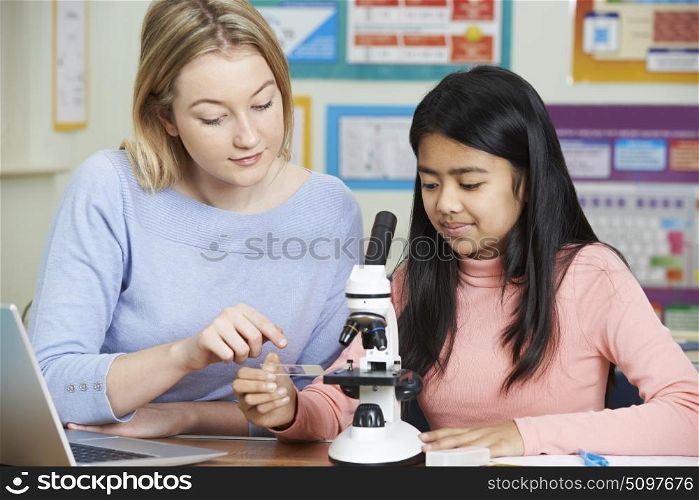 Teacher With Female Student Using Microscope In Science Class