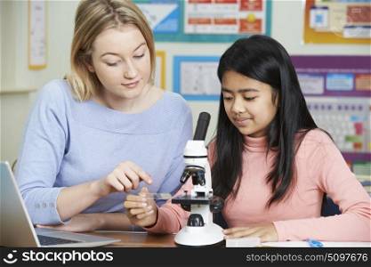 Teacher With Female Student Using Microscope In Science Class