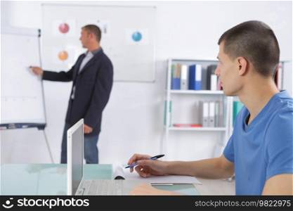 teacher with notepad showing scheme on white board in classroom