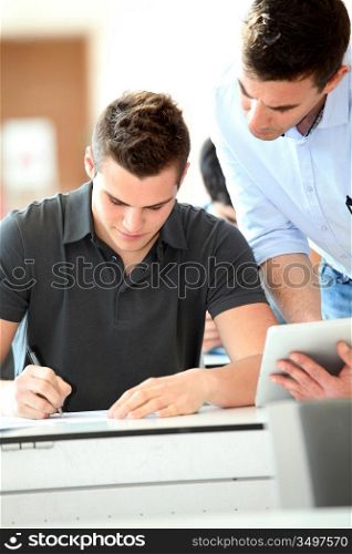 Teacher with tablet helping student with exam