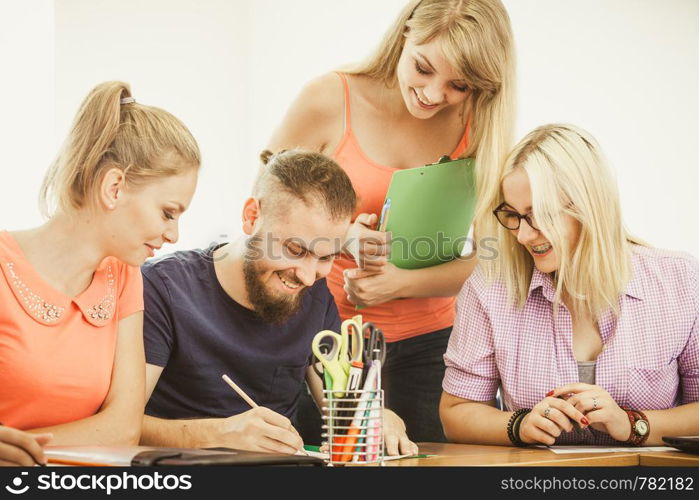 Teaching Concept. Female young teacher or tutor with adult students in classroom with papers, laptop computer. Studies course. Students and teacher tutor in classroom