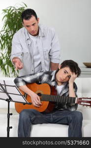 Teaching son how to play guitar.