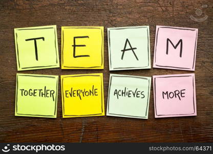 TEAM acronym (together everyone achieves more), teamwork motivation concept, handwriting on a colorful sticky notes against rustic wood