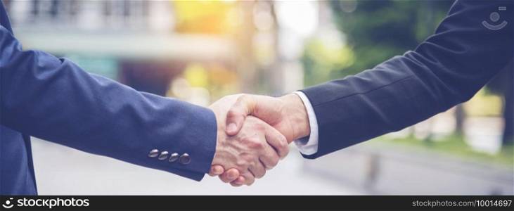 Team Business Partners shaking hands together to Greeting Start up new project. Shakehand Teamwork Partnership outside office modern city background. Businessman handshake together.  Business concept
