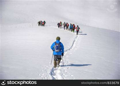Team of alpinists crossing a glacier. Command of people in snow. One man going behind. Tourism concept.