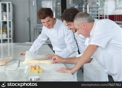 team of bakers kneading dough in a commercial kitchen