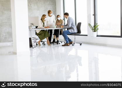 Team of business people working on project with facial masks as a virus protection in the office