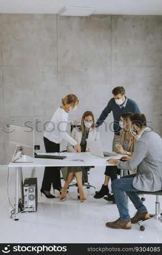 Team of business people working on project with facial masks as a virus protection in the office