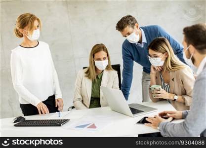 Team of business people working on project with facial masks as a virus protection in the office