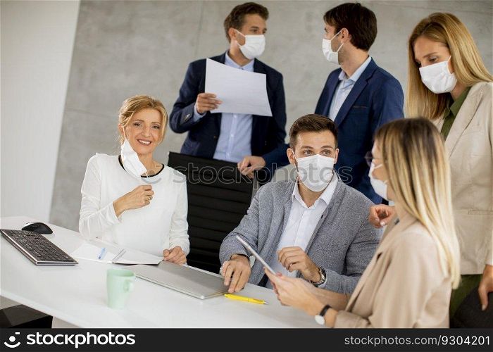 Team of business people working on project with facial masks as a virus protection in the office
