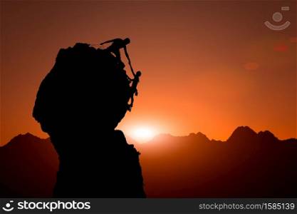 Team of climbers help to conquer the summit in teamwork during a climb roped in a fantastic mountain landscape at sunset