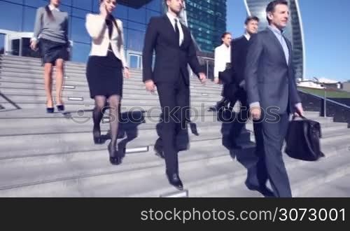 Team of diverse business people go down the stairs of company office building