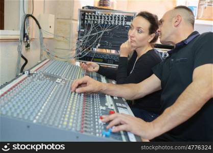 team of engineers working at mixing desk in recording studio