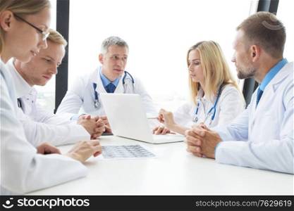 Team of experts doctors examining mri report on hospital office meeting. Team of expert doctors at clinic