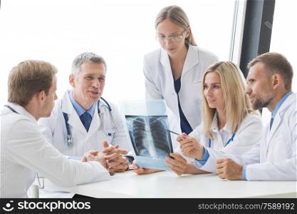 Team of experts doctors examining X-ray report on hospital office meeting. Team of expert doctors with x-ray