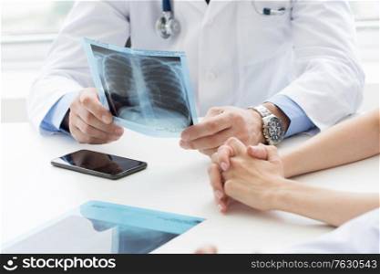 Team of experts doctors examining X-ray report on hospital office meeting. Team of expert doctors with x-ray
