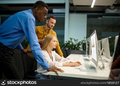 Team of managers looks on screen in IT office. Professional teamwork and planning, group brainstorming and corporate work, modern company interior on background. Team of managers looks on screen in IT office