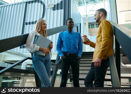 Team of managers talks on stairs in IT office. Professional teamwork and planning, group brainstorming and corporate work, modern company interior on background. Team of managers talks on stairs in IT offic