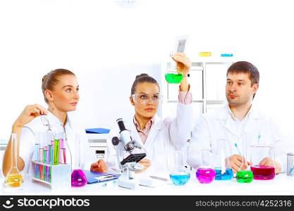 Team of scientists working with liquids in laboratory