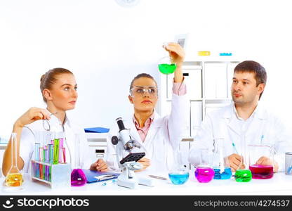 Team of scientists working with liquids in laboratory