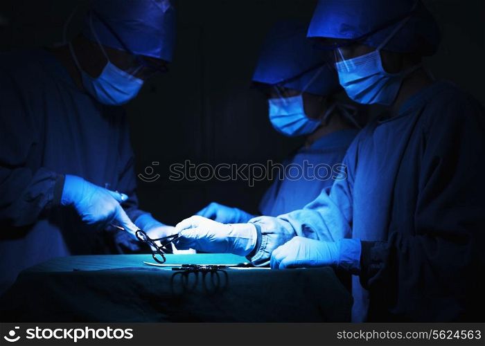 Team of surgeons holding surgical equipment at the operating table and working
