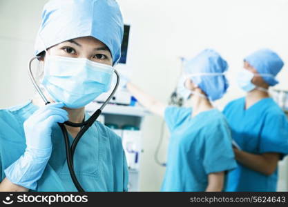 Team of surgeons in the operating room, female surgeon holding stethoscope and looking at camera