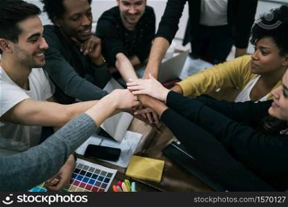 Team of work of creative designers showing unity with their hand together during meeting. Business and team work concept.
