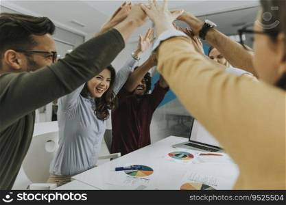 Team of young people stacking hands together over table engaged in teambuilding