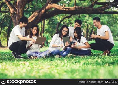 Team of young students studying in a group project in the park of university or school. Happy learning, community teamwork and youth friendship concept.