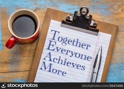TEAM - together everyone achieves more - motivational text on a clipboard with a cup of coffee