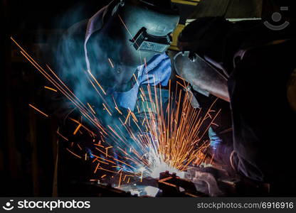 Team welder are welding automotive part in factory