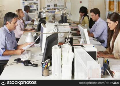 Team Working At Desks In Busy Office