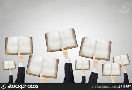 Teamwork and collaboration concept. Group of business people holding books in raised hands